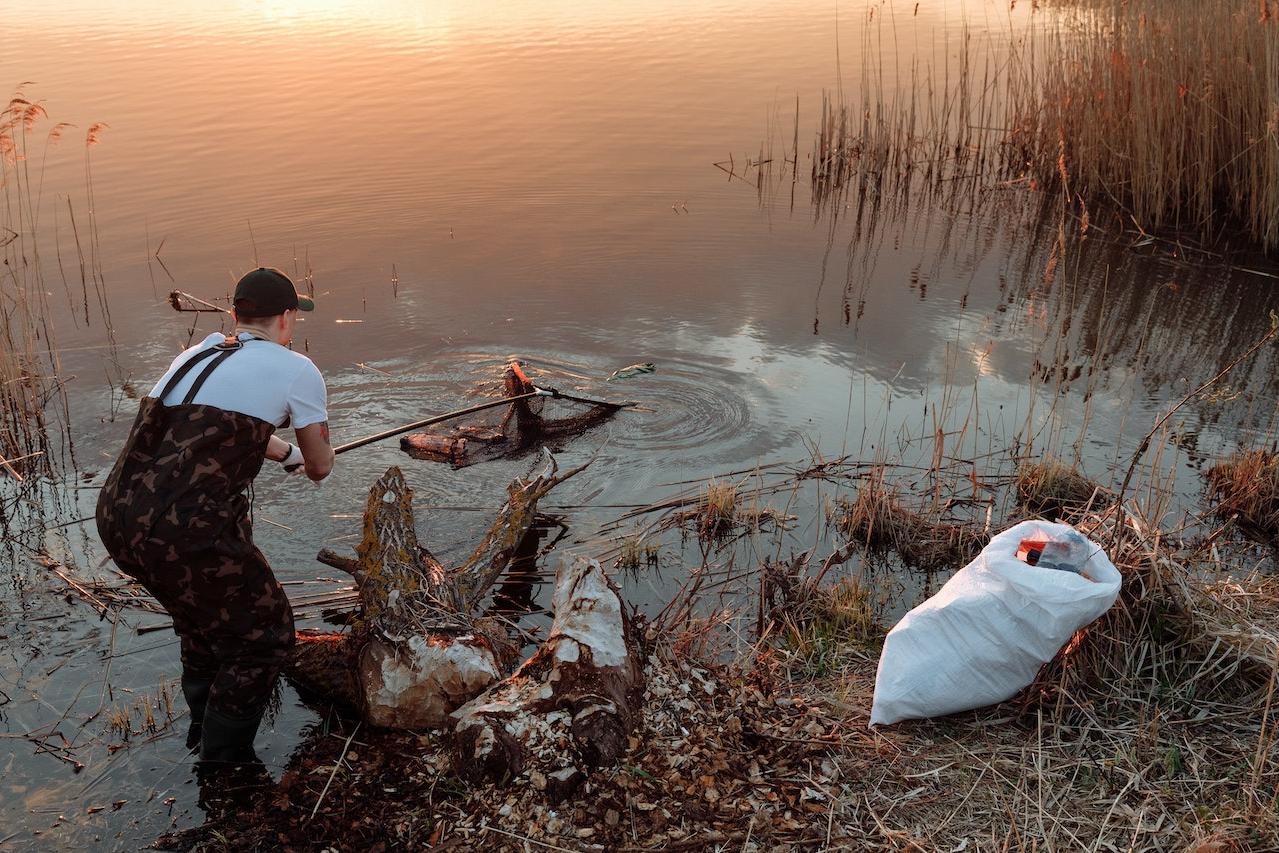 Man cleaning trash from a lake